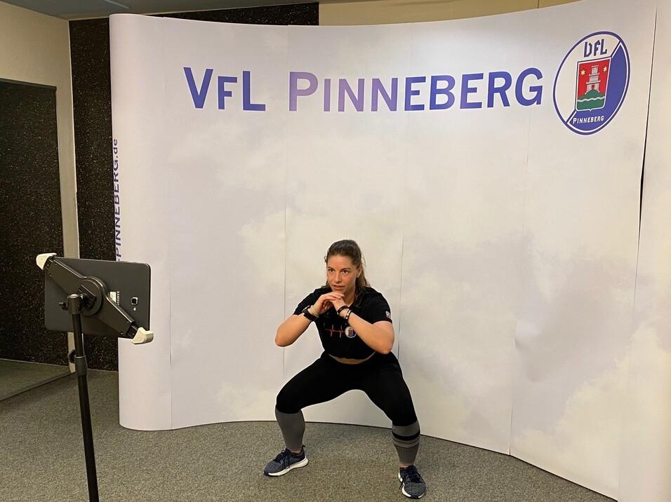 Frau in Sportkleidung führt eine Kniebeuge vor einem Hintergrund mit dem Logo von VfL Pinneberg aus.