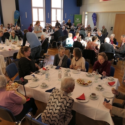 Geselliges Beisammensein von älteren Menschen an festlich gedeckten Tischen in einem gut beleuchteten Raum.