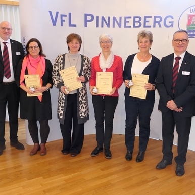 Gruppe von Personen in formeller Kleidung hält Urkunden vor einem Banner mit der Aufschrift „VfL Pinneberg“.
