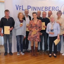 Erwachsene Gruppenaufnahme mit Auszeichnungen und Urkunden vor einem VfL Pinneberg Banner.