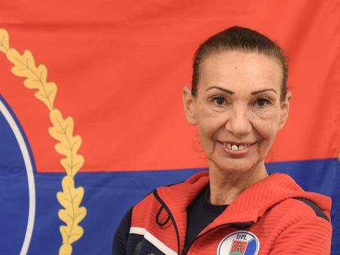 Porträt einer Frau im Sportanzug vor der Flagge von Pinneberg mit Wappen und blauen sowie roten Farben.