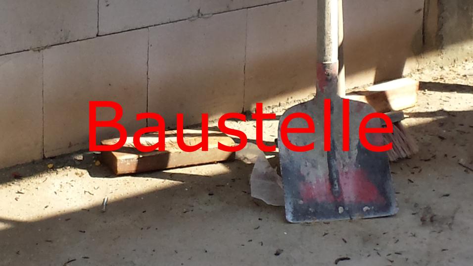 Schaufel und Besen auf einem Bauplatz, umgeben von Erde und Mauerwerksteilen.