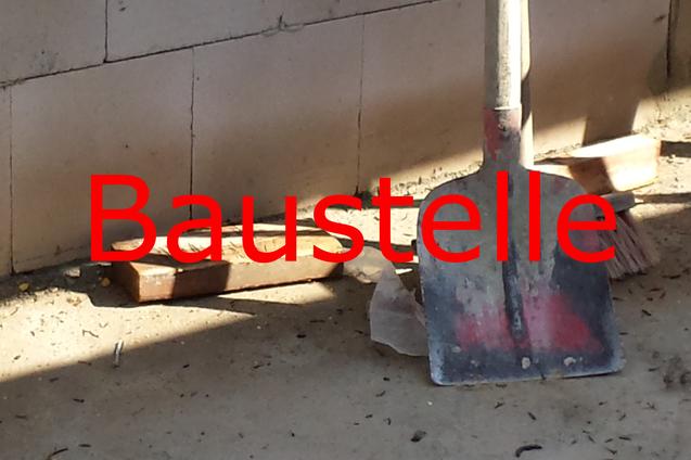 Schaufel und Besen auf einem Bauplatz, umgeben von Erde und Mauerwerksteilen.