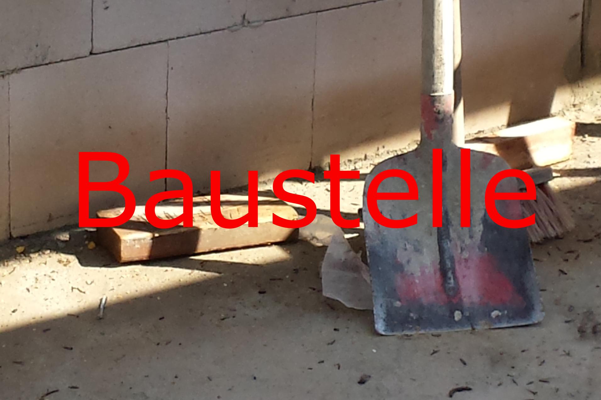 Schaufel und Besen auf einem Bauplatz, umgeben von Erde und Mauerwerksteilen.