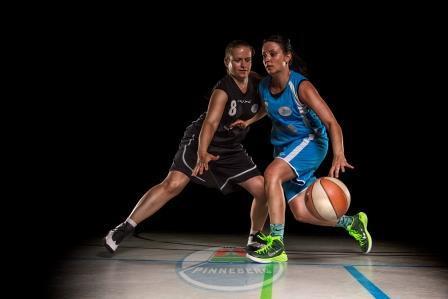 Zwei Basketballspielerinnen in Aktion, eine in schwarzer und eine in blauer Kleidung, dribbeln auf dem Spielfeld.
