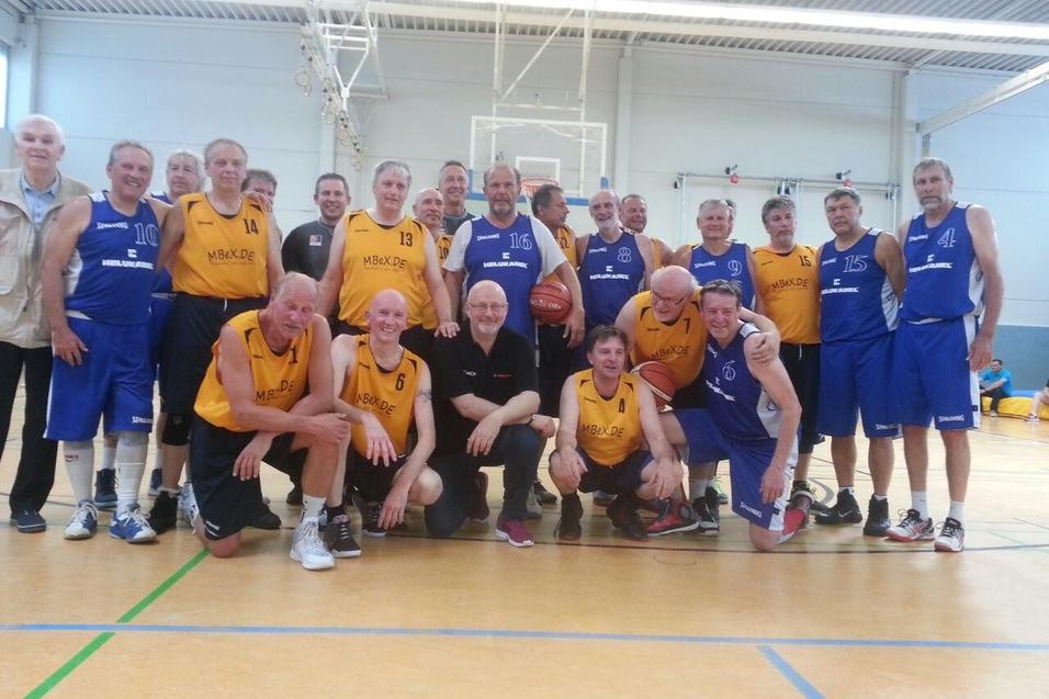 Gruppenfoto von &auml;lteren Basketballspielern in gelben und blauen Trikots in einer Sporthalle.