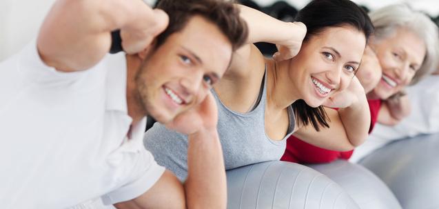 Drei Personen machen Übungen auf Gymnastikbällen in einem hellen Fitnessraum.