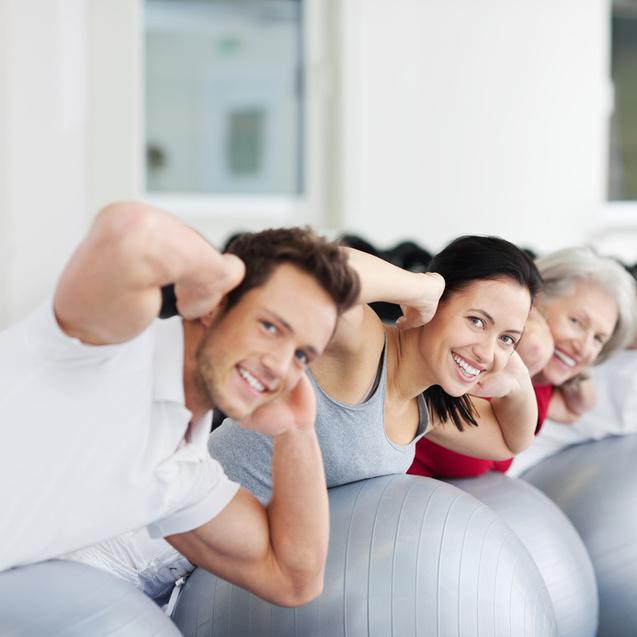 Drei Personen machen Übungen auf Gymnastikbällen in einem hellen Fitnessraum.