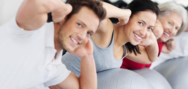 Drei Personen machen Übungen auf Gymnastikbällen in einem hellen Fitnessraum.