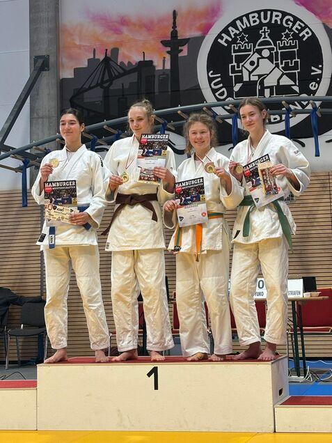 Vier Judoka stehen auf dem Siegertreppchen, halten Medaillen und Urkunden in der Sporthalle in Hamburg.