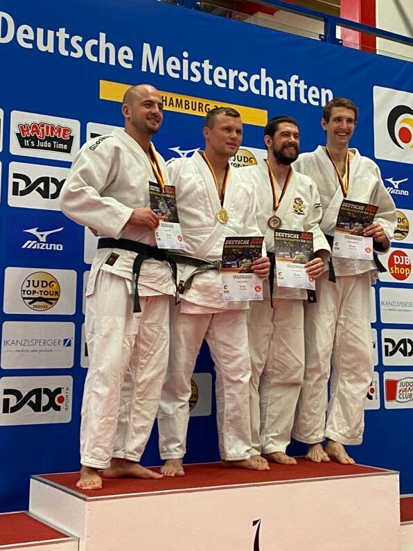 Vier Judoka in wei&szlig;en Anz&uuml;gen stehen auf dem Siegertreppchen der Deutschen Meisterschaften und halten Medaillen und Urkunden.