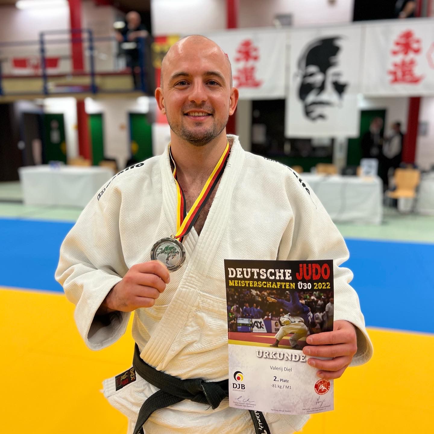 Sportler in einem Judoanzug hält Silbermedaille und Urkunde für den zweiten Platz bei den Deutschen Meisterschaften 2022.