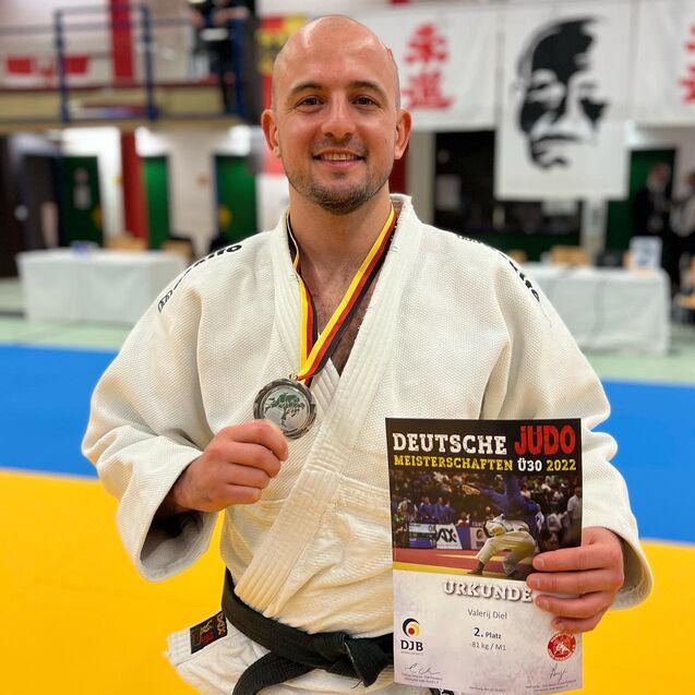 Sportler in einem Judoanzug h&auml;lt Silbermedaille und Urkunde f&uuml;r den zweiten Platz bei den Deutschen Meisterschaften 2022.