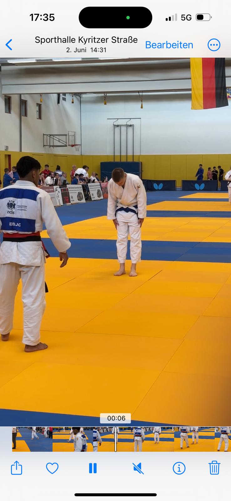 Zwei Judokas in einer Sporthalle, einer verbeugt sich auf der gelben Matte während der Wettkampf läuft.