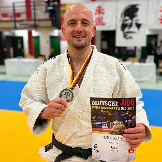 Sportler in einem Judoanzug hält Silbermedaille und Urkunde für den zweiten Platz bei den Deutschen Meisterschaften 2022.