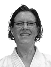 Porträt einer lächelnden Person in einem weißen Judogi mit einem leichten Hintergrund.