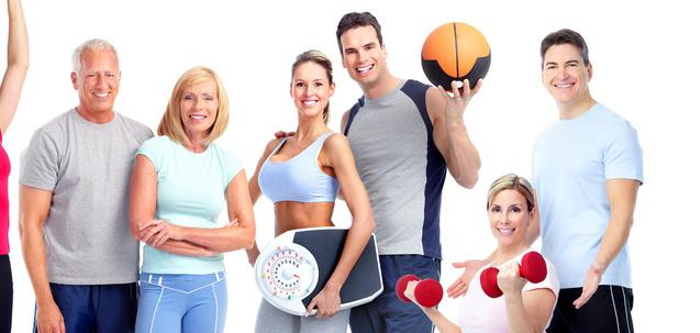 Gruppe von Fitnessbegeisterten in Sportkleidung, einige halten Hanteln, ein Medizinball und ein Balancegerät.