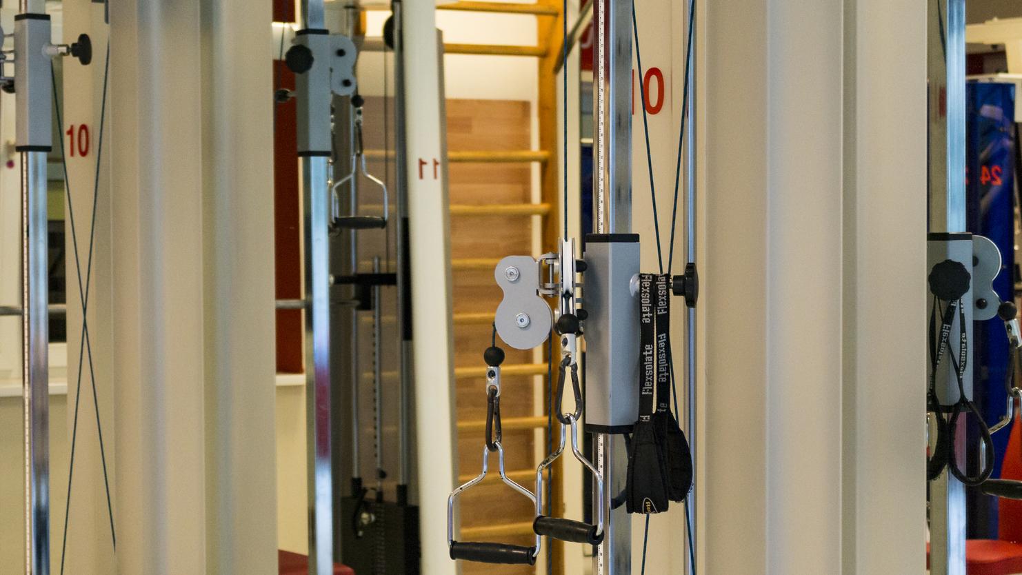 Nahaufnahme von Fitnessgeräten in einem modernen Studio mit Kettlebells und Kabelzugstationen.