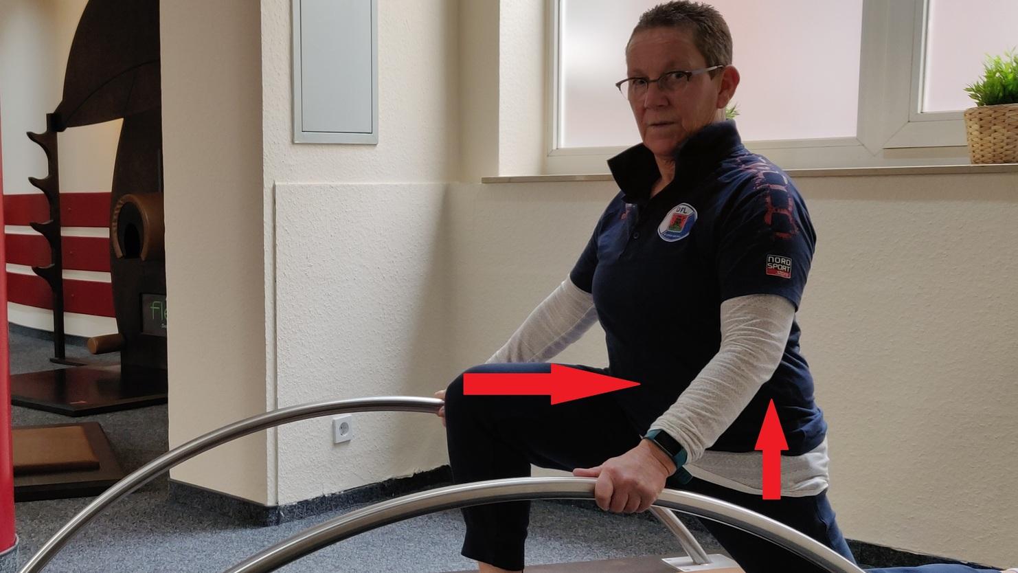 Frau in Sportkleidung macht eine Übung auf einem Trainingsgerät in einem Fitnessraum.