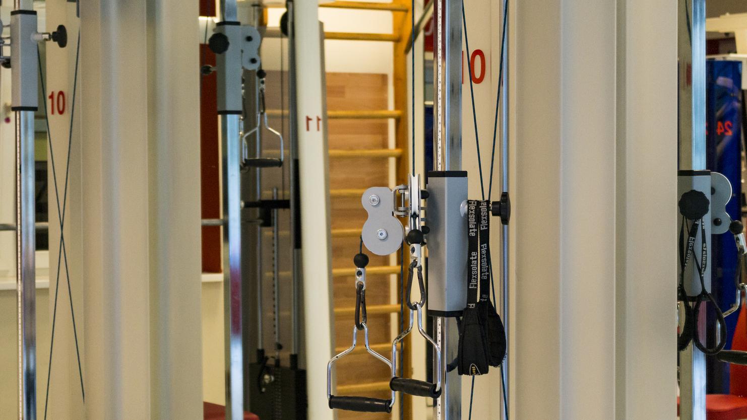 Nahaufnahme von Fitnessgeräten in einem modernen Studio mit Kettlebells und Kabelzugstationen.