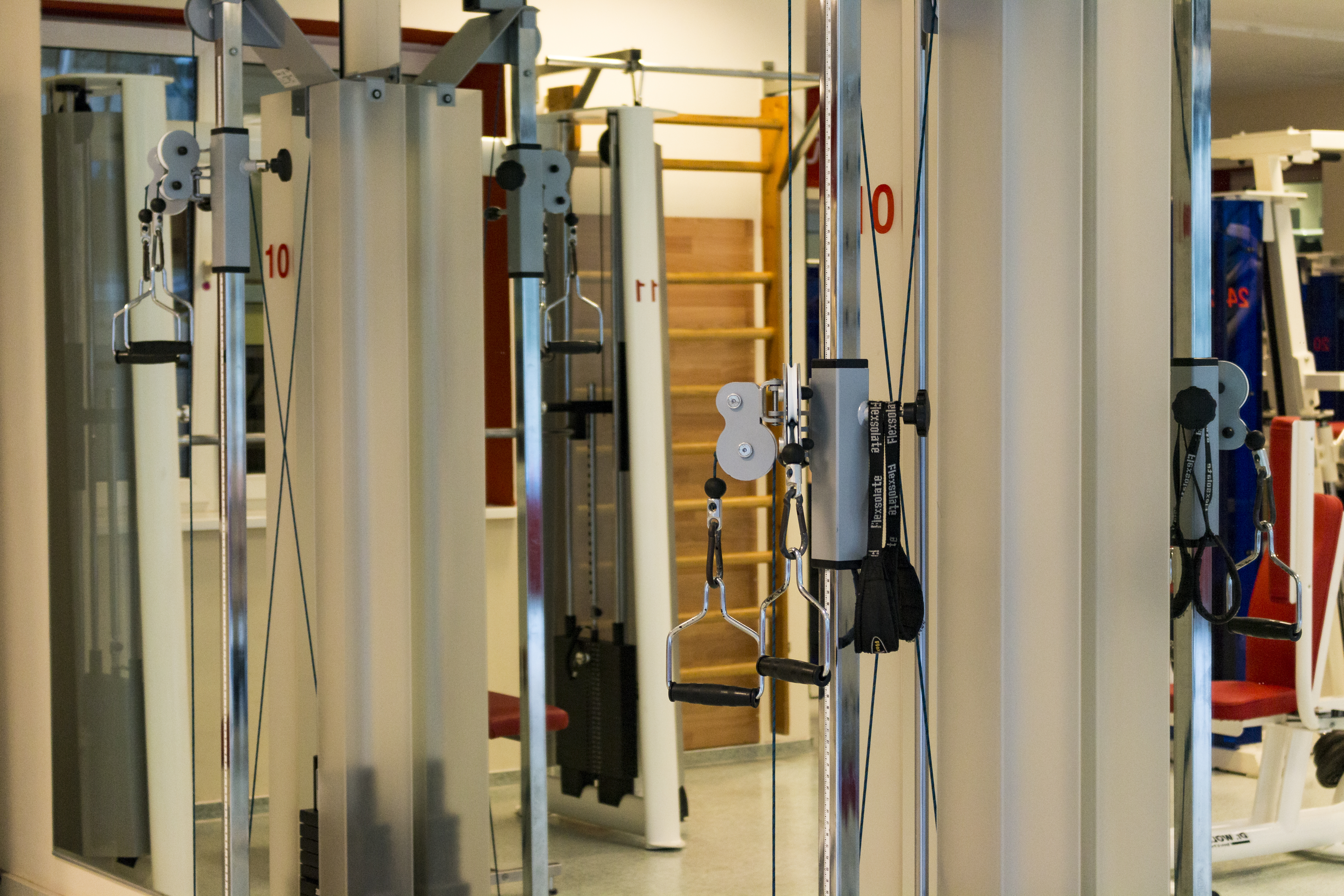 Nahaufnahme von Fitnessgeräten in einem modernen Studio mit Kettlebells und Kabelzugstationen.