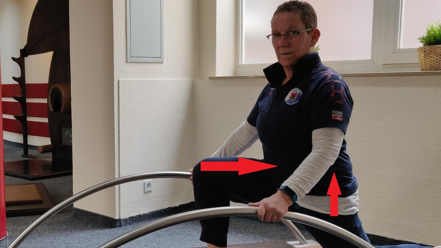 Frau in Sportkleidung macht eine Übung auf einem Trainingsgerät in einem Fitnessraum.