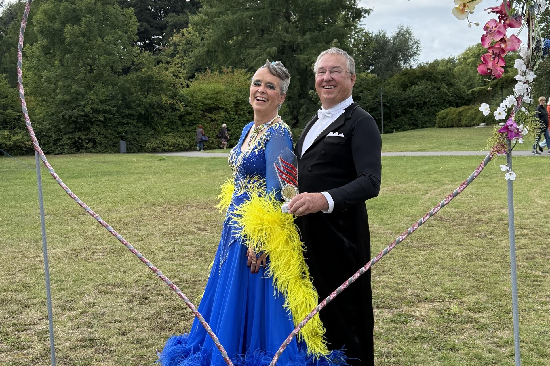 Manuela & Dieter Meerkatz Aufstiegsfoto Senioren Tanzpaar hinter Herzförmigen Fotorahmen auf einer Wiese