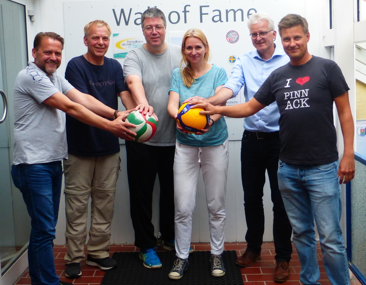 Sechs Personen stehen vor einer Wand mit dem Schriftzug „Wall of Fame“ und halten Sportbälle in den Händen.