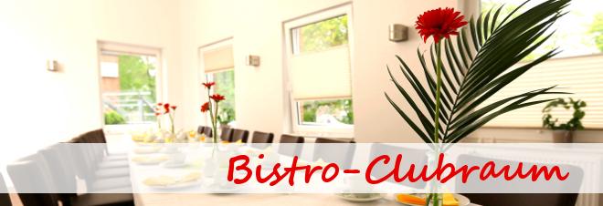 Blick in einen hellen Bistro-Clubraum mit Tisch, Blumen und Stühlen entlang der Wände.