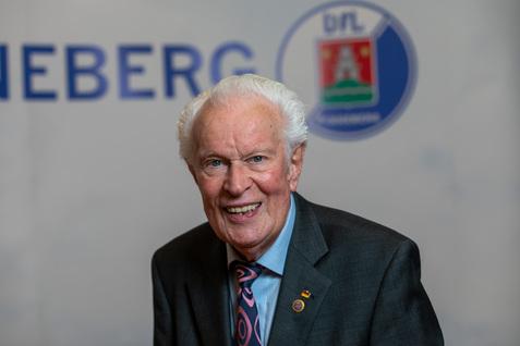 Älterer Mann mit grauen Haaren in einem Anzug, lächelnd vor einem Hintergrund mit dem Schriftzug „DIEBERG“.